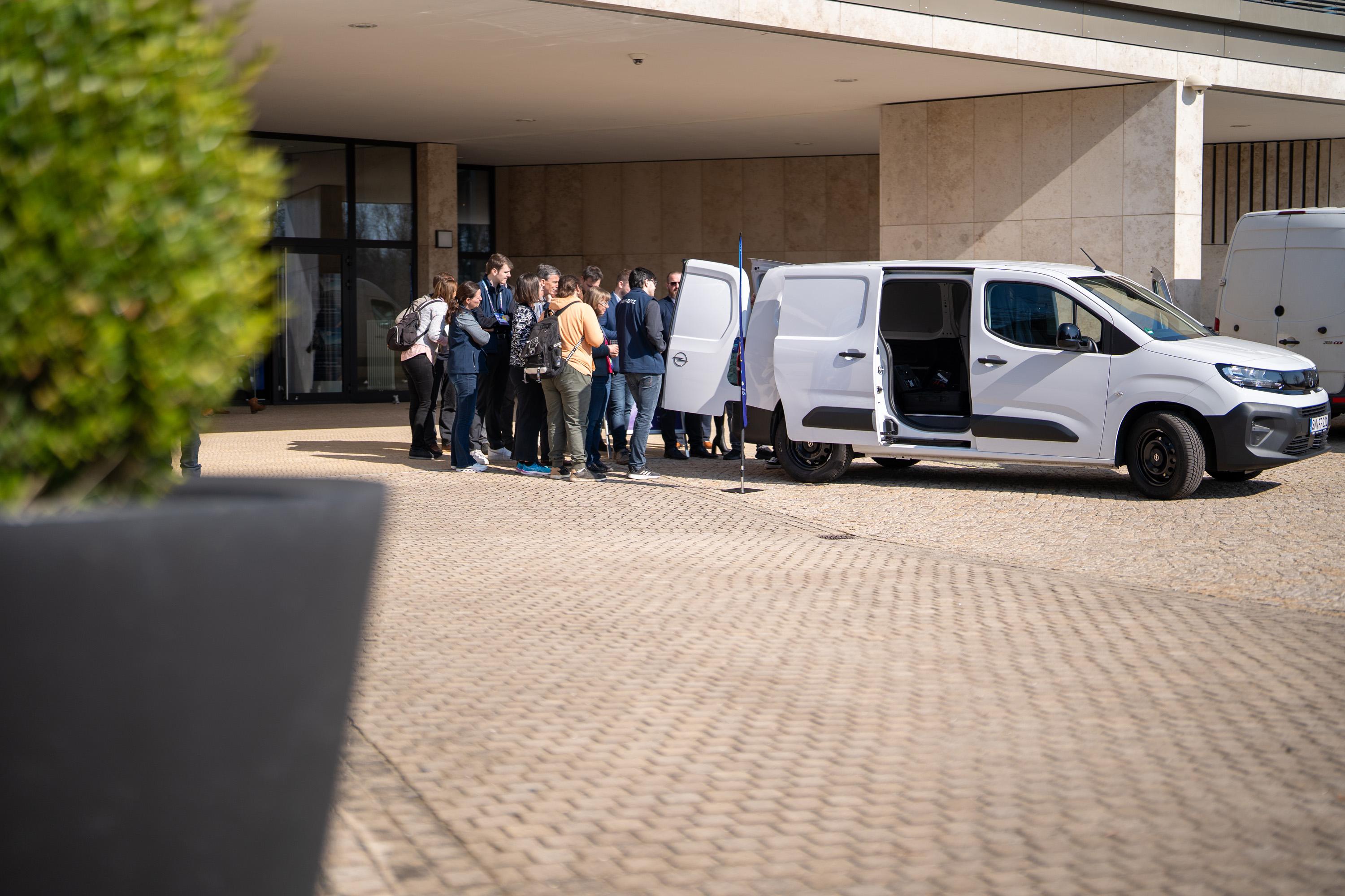 Gruppe von Menschen steht vor einem weißen Lieferwagen vor der IHK zu Schwerin, wo Car Forensik präsentiert wird.